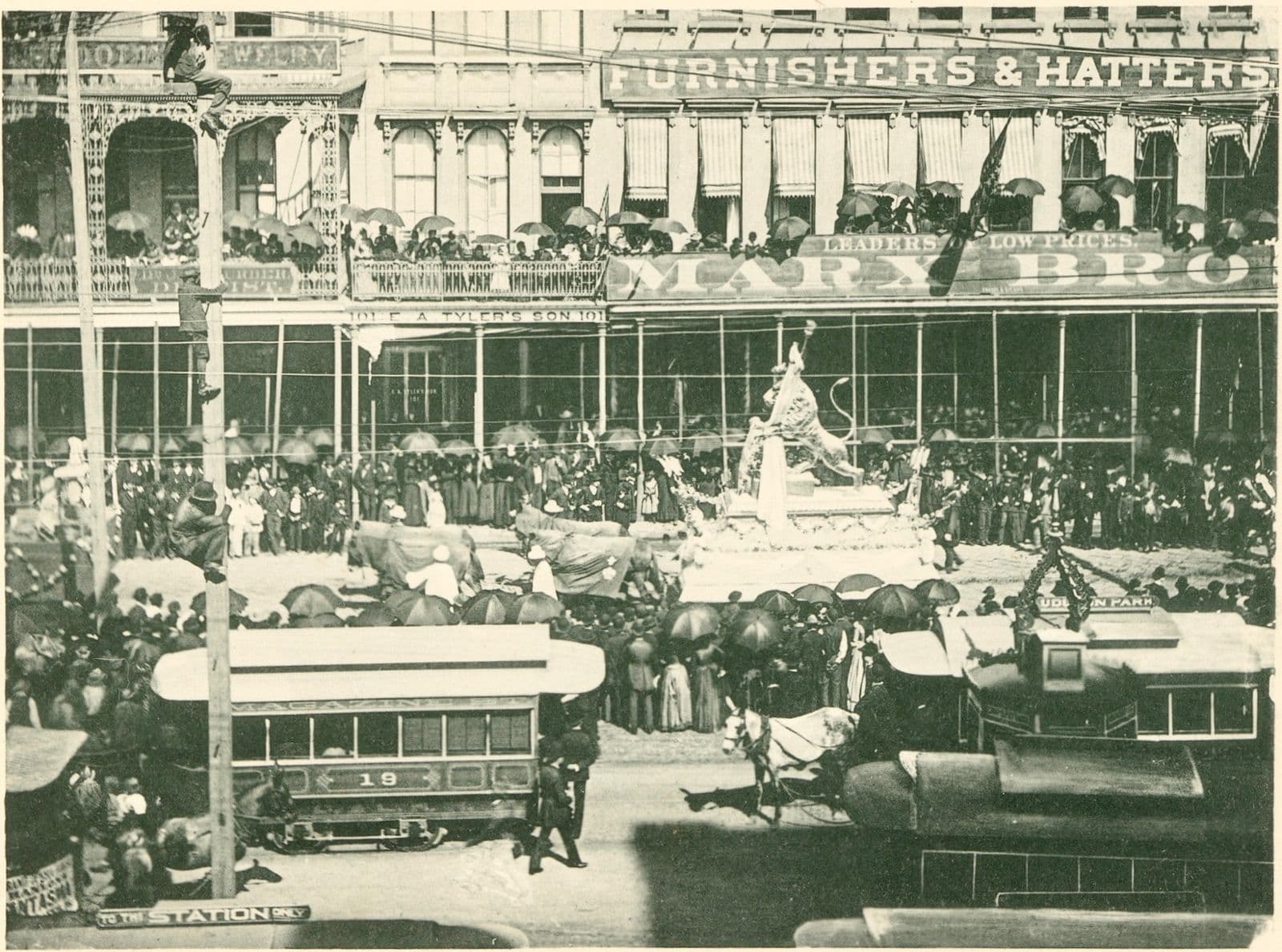 Archival photo of the first float of the 1890 Rex parade on Canal Street, with crowds packing the street and balconies