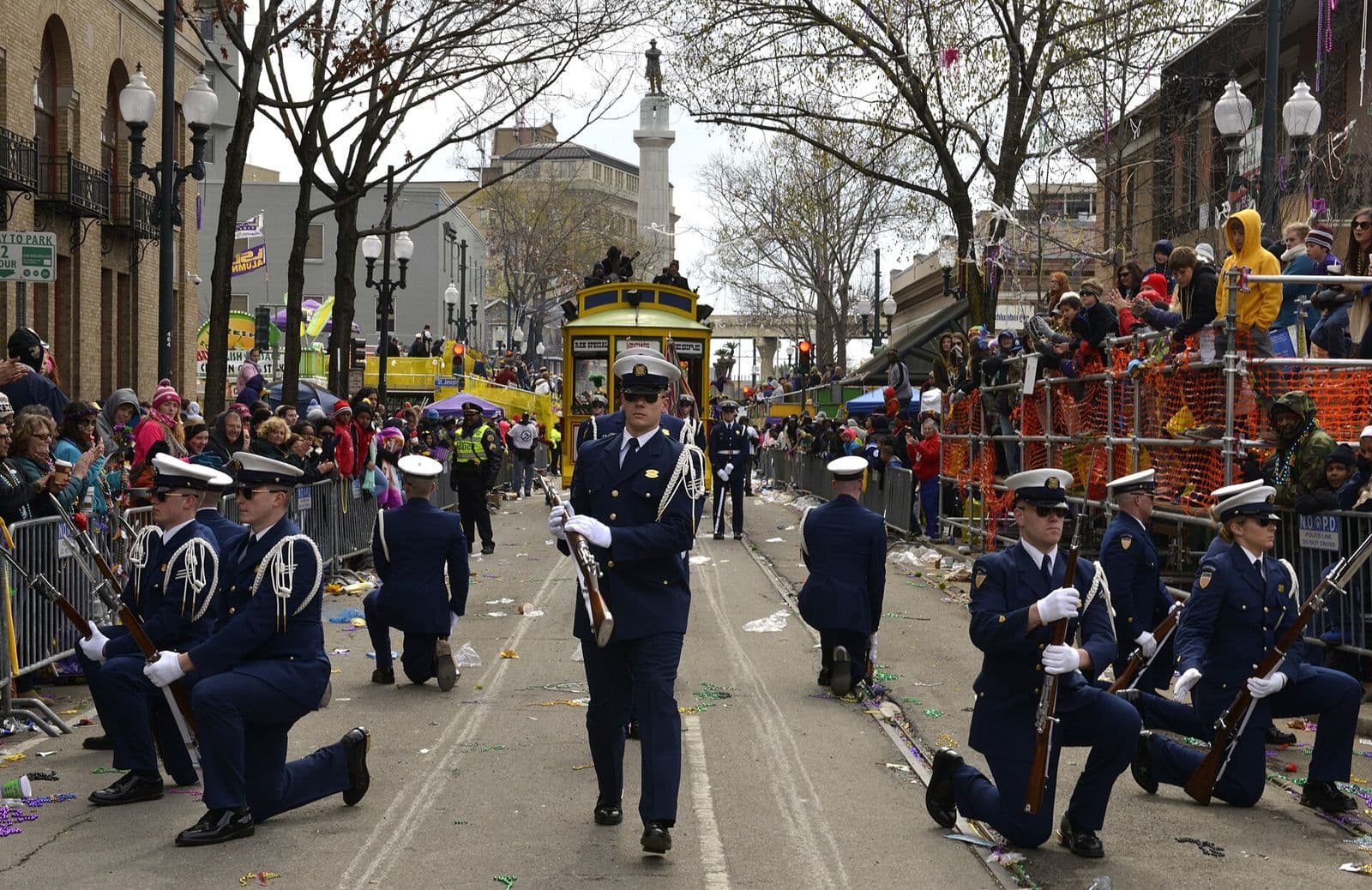 A U.S. Coast Guard honour guard marching on St. Charles Avenue in the Rex parade, with crowds and grandstands lining the route