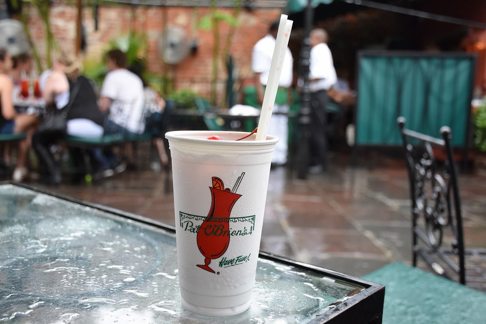 A Pat O'Brien's Hurricane in a branded cup on a rain-covered table in the courtyard