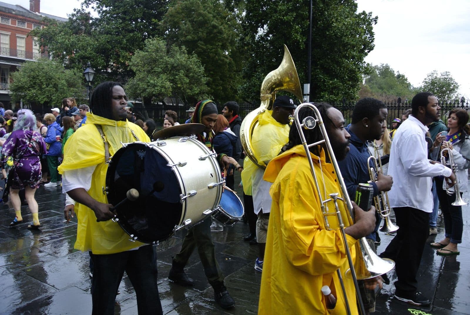 A brass band in yellow rain gear playing on a wet French Quarter street during the Barkus parade