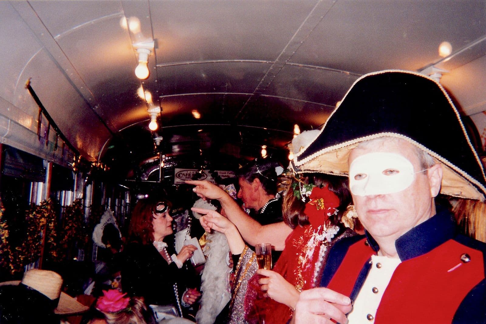 A masked Phunny Phorty Phellows member in a bicorne hat aboard the St. Charles streetcar on Twelfth Night